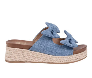 Add the perfect touch of charm to your warm-weather wardrobe with The Cosmos Wedge. Featuring a beautiful denim-inspired upper adorned with feminine bow details, this stylish wedge combines playful design with all-day comfort. The braided espadrille platform adds a classic summer feel, making it the perfect choice for everything from casual outings to vacation adventures. Pair it with your favorite dresses, denim, or shorts for an effortlessly chic look.

DETAILS:

Denim-look textured upper
Double bow 