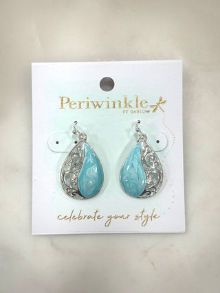 Soft, coastal tones meet elegant detail in the Seafoam Swirl Teardrop Earrings. Featuring a marbled aqua center framed by delicate silver scrollwork, these earrings bring movement, shine, and just the right pop of color to any look.

Details
• Silver-tone setting
• Teardrop silhouette
• Marbled aqua swirl center
• Lightweight dangle style
• Easy hook closure