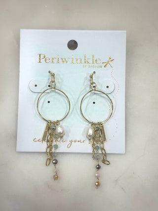 Soft sparkle meets effortless movement with the Golden Drift Charm Hoop Earrings. Featuring delicate gold hoops adorned with layered chains, a luminous pearl accent, and subtle bead details, this pair adds texture, shine, and a touch of whimsy to any look. Lightweight with beautiful sway, they’re perfect for dressing up a simple outfit or adding interest to your everyday style.

Details
• Gold-tone hoop earrings
• Layered chain and charm accents
• Pearl and bead detailing
• Lightweight with fluid movement
