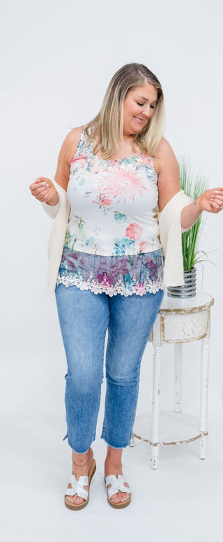 Soft, feminine, and beautifully detailed — the Blushing Garden Lace Hem Tank adds a romantic touch to your everyday wardrobe. Featuring a delicate watercolor-style floral print, this sleeveless top blends soft pastel tones with effortless elegance.

The standout detail is the intricate lace trim along the hem, creating a layered look that adds texture and charm. Lightweight and easy to wear, this tank pairs perfectly with denim, shorts, or layered under a cardigan for a polished yet comfortable outfit.
