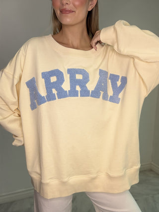 Cozy meets statement style in the Sunburst ARRAY Sweater. Featuring a soft, sunny yellow base with bold “ARRAY” lettering across the front, this piece adds a fun, standout touch to your everyday wardrobe.

Designed with a relaxed silhouette and ultra-soft feel, it’s perfect for laid-back days while still keeping your look effortlessly put together.

DETAILS:

• Soft fleece feel
• “ARRAY” graphic lettering
• Relaxed, easy silhouette
• Classic crew neckline
• Ribbed cuffs and hem
• Comfortable everyday style
