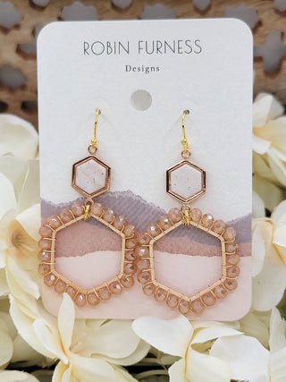 Pair of gold hexagonal earrings on a 'Robin Furness Designs' card with flowers in the background
